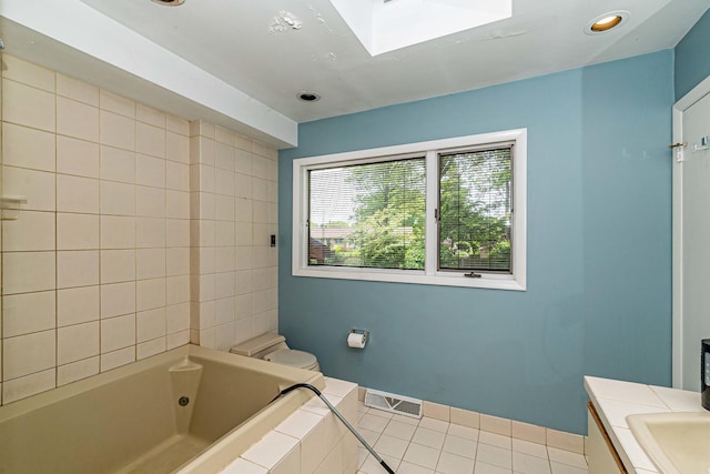 bathroom featuring tile floors, toilet, vanity, and a skylight