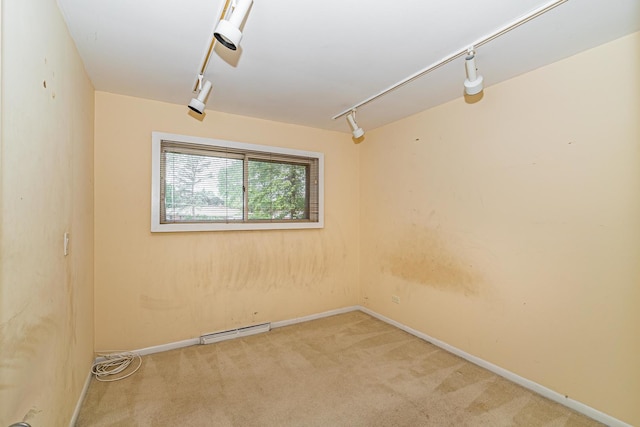 spare room with a baseboard radiator, track lighting, and light carpet