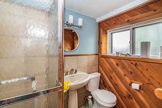 bathroom with toilet and tile walls