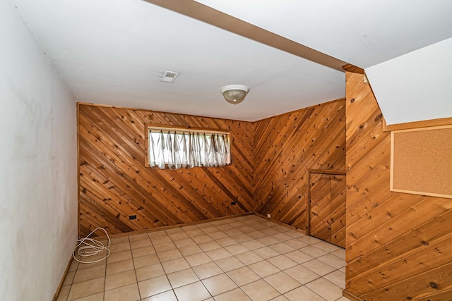 spare room featuring wooden walls and light tile floors