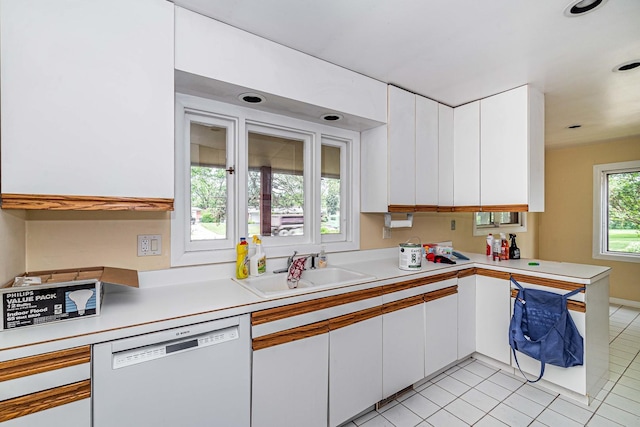 kitchen with white dishwasher, white cabinets, light tile floors, and sink