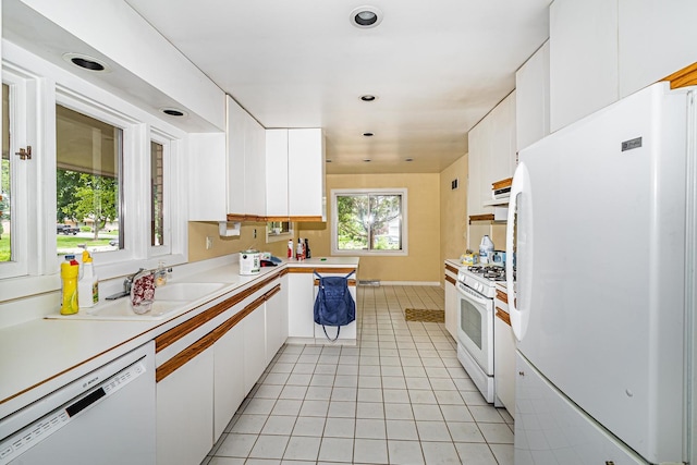 kitchen with white appliances, white cabinets, light tile floors, and sink