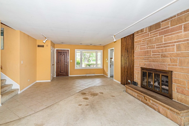 unfurnished living room featuring track lighting, light carpet, and a fireplace