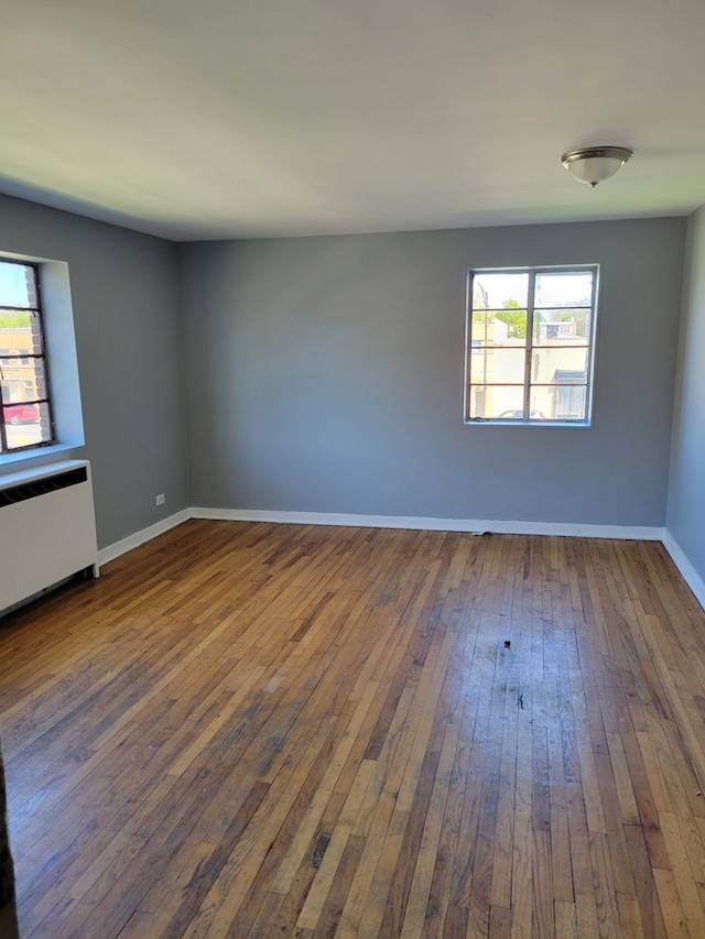 spare room featuring dark wood-type flooring and radiator