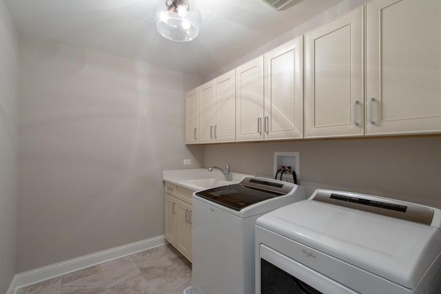 clothes washing area featuring washer hookup, sink, light tile flooring, cabinets, and washer and dryer