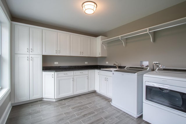 clothes washing area with cabinets, sink, light hardwood / wood-style flooring, washer hookup, and washing machine and clothes dryer