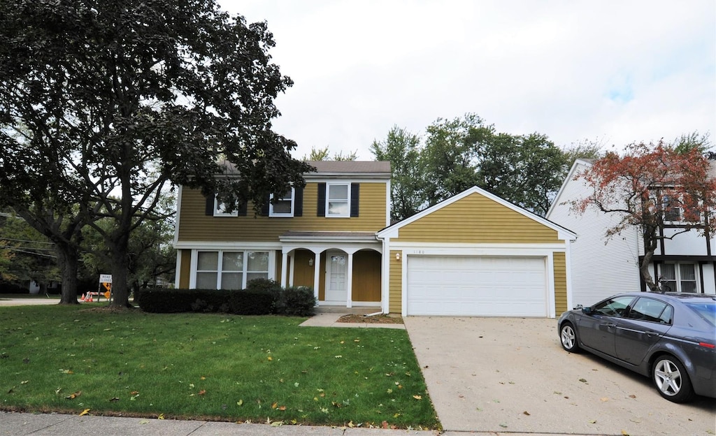 colonial inspired home featuring a front lawn and a garage