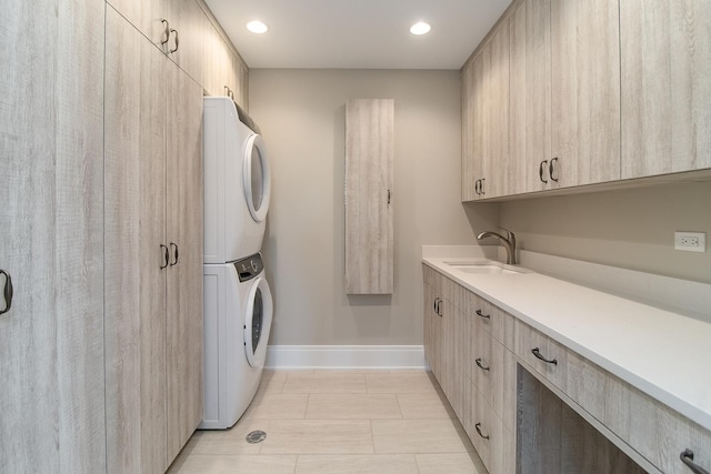 laundry room with sink, cabinets, stacked washer / drying machine, and light tile floors