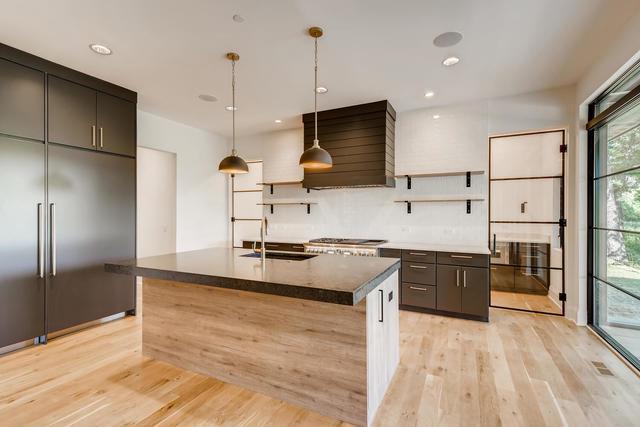 kitchen with hanging light fixtures, premium range hood, light hardwood / wood-style floors, sink, and a kitchen island with sink