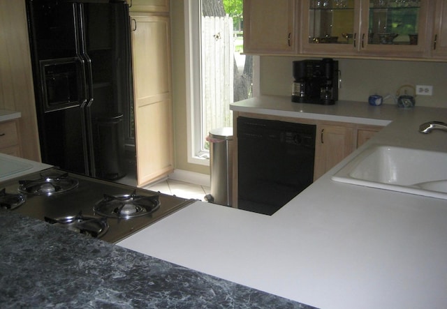 kitchen with a wealth of natural light, light tile floors, black appliances, and sink