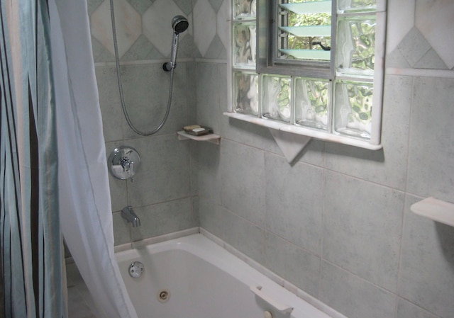 bathroom with shower / bath combo with shower curtain and tile walls