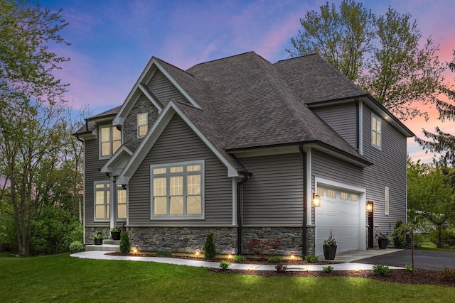 view of front of house with a shingled roof, stone siding, driveway, and a front lawn