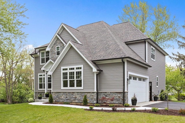 craftsman house with stone siding, a front lawn, roof with shingles, and driveway