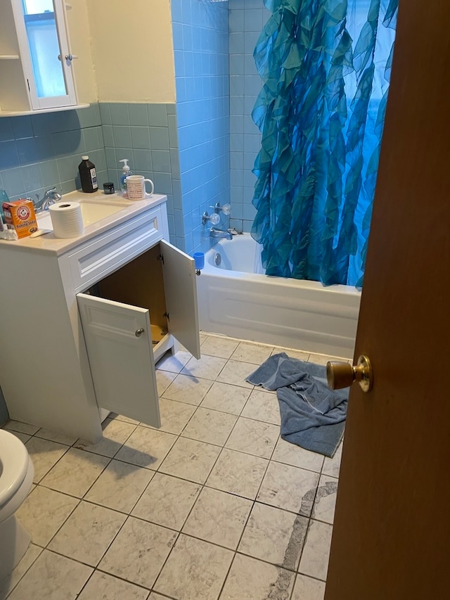 full bathroom featuring shower / bath combo with shower curtain, toilet, vanity, backsplash, and tile walls