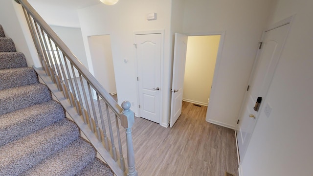 stairs featuring a towering ceiling and light hardwood / wood-style flooring