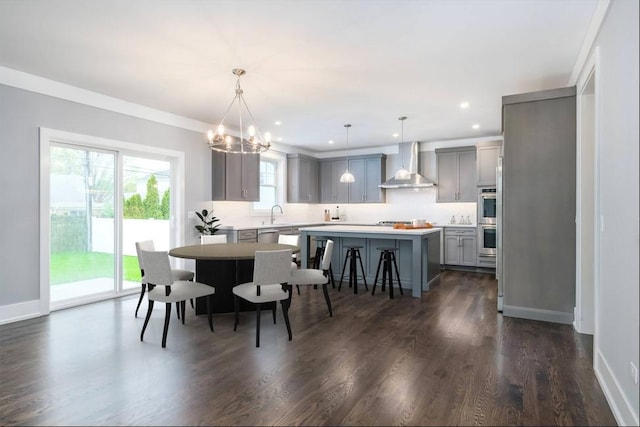 dining area with a chandelier, dark hardwood / wood-style floors, sink, and ornamental molding