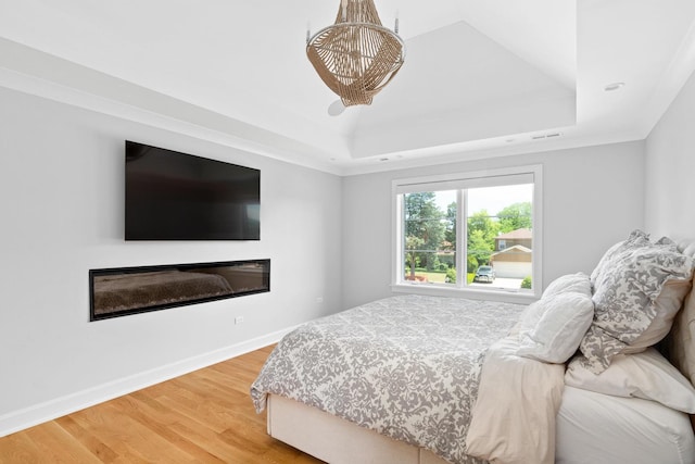 bedroom featuring a tray ceiling and light wood-type flooring