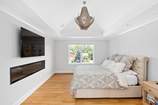 bedroom featuring lofted ceiling, a tray ceiling, and light hardwood / wood-style floors