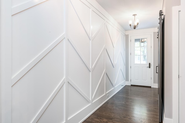 doorway to outside with a barn door, an inviting chandelier, and dark hardwood / wood-style flooring