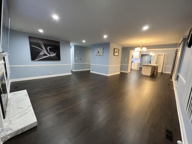 unfurnished living room with dark hardwood / wood-style floors, a notable chandelier, and a premium fireplace