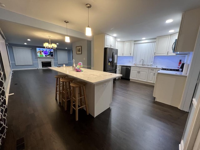 kitchen with white cabinets, dark hardwood / wood-style floors, decorative light fixtures, a kitchen island, and stainless steel appliances