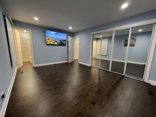 unfurnished bedroom featuring a closet, dark hardwood / wood-style flooring, and ensuite bath