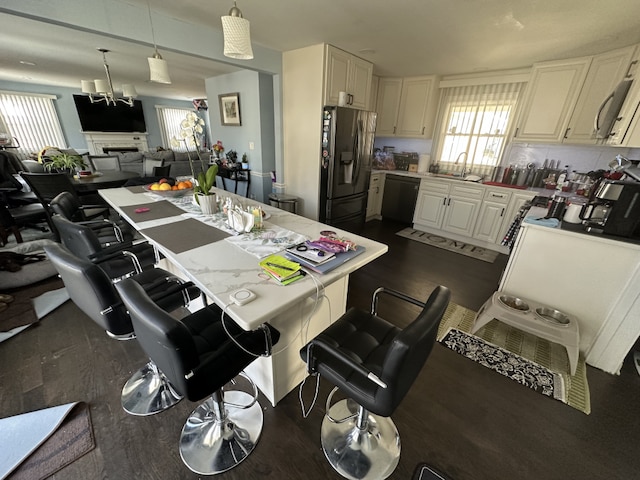 kitchen featuring a kitchen breakfast bar, sink, decorative light fixtures, dishwasher, and stainless steel fridge with ice dispenser