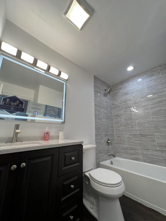 full bathroom with hardwood / wood-style flooring, vanity, tiled shower / bath combo, and toilet