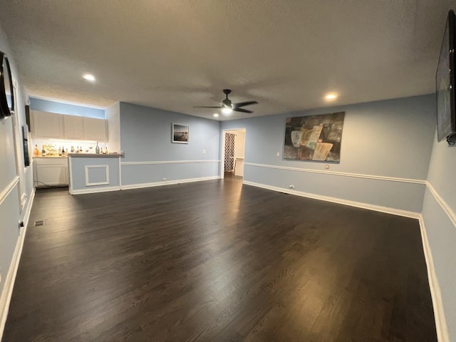 unfurnished living room with a textured ceiling, ceiling fan, and dark hardwood / wood-style floors