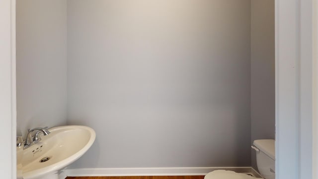 bathroom featuring sink, wood-type flooring, and toilet