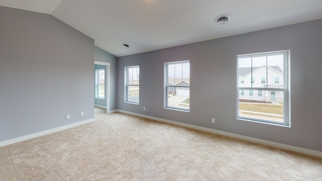 carpeted empty room with vaulted ceiling