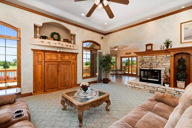 living room with ceiling fan, ornamental molding, a fireplace, and light colored carpet