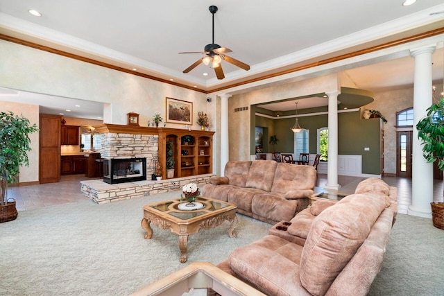 carpeted living room featuring ornamental molding, decorative columns, a fireplace, and ceiling fan