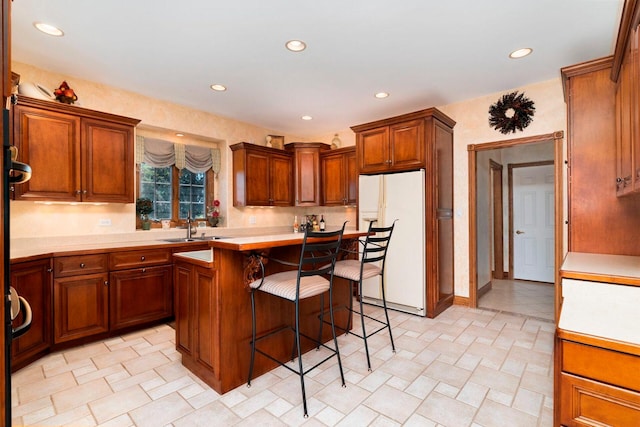 kitchen with white fridge with ice dispenser, sink, light tile floors, a kitchen island, and a breakfast bar area