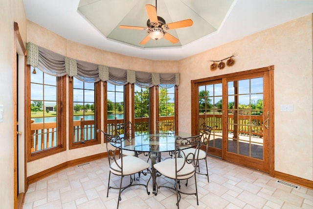 interior space featuring ceiling fan, a water view, and a tray ceiling