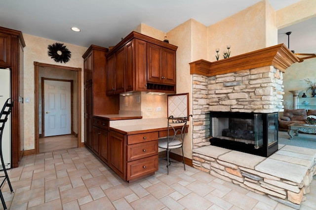 kitchen with a fireplace, built in desk, light tile floors, and tasteful backsplash