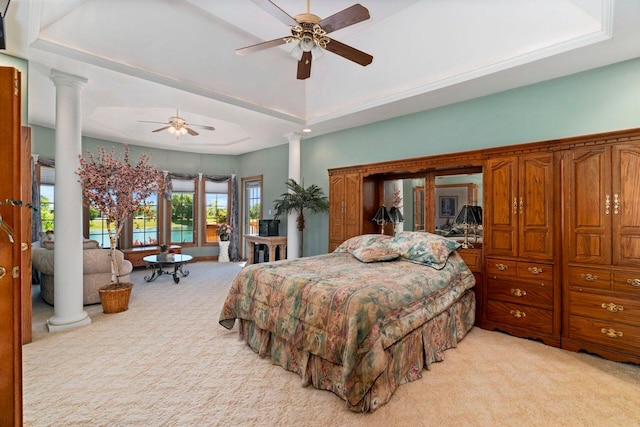 carpeted bedroom featuring a raised ceiling, decorative columns, and ceiling fan