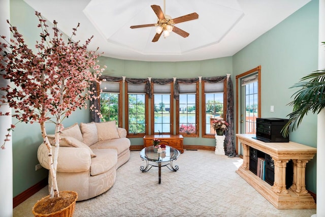 carpeted living room featuring ceiling fan, a wood stove, and a raised ceiling