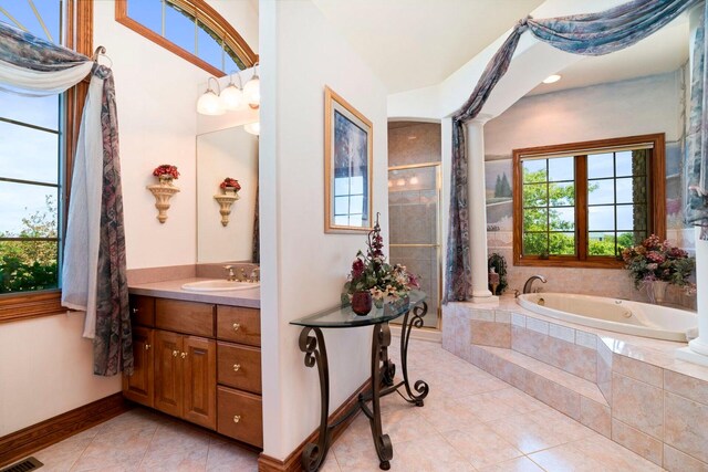 bathroom featuring vanity with extensive cabinet space, tile flooring, tiled tub, and ornate columns