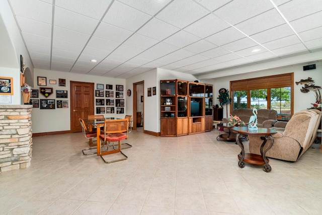 living room featuring a drop ceiling and light tile floors