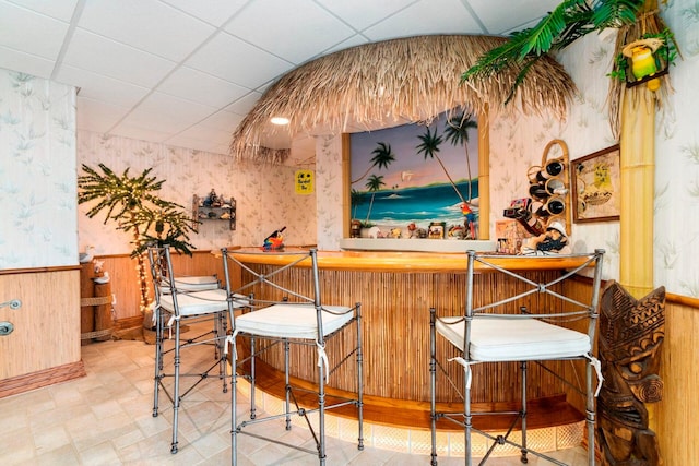 bar featuring a drop ceiling and light tile floors