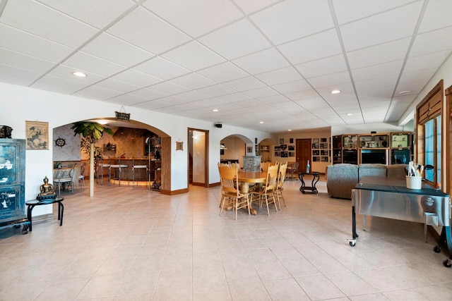 living room featuring a paneled ceiling and light tile flooring