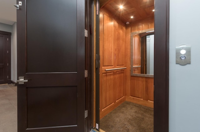 details featuring dark tile floors, wood walls, and elevator