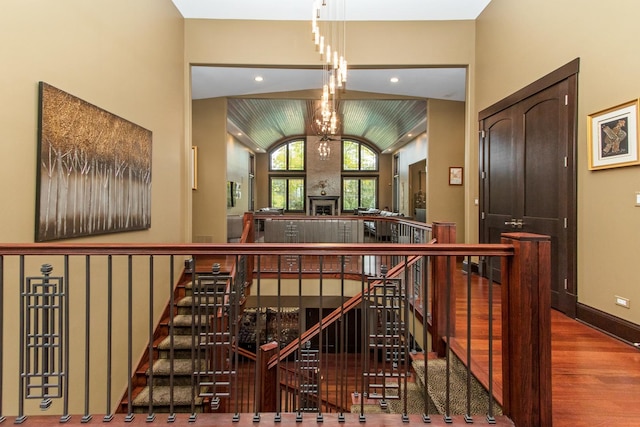 corridor with an inviting chandelier, lofted ceiling, and dark hardwood / wood-style flooring