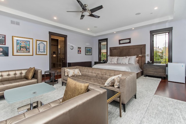 bedroom with a raised ceiling, hardwood / wood-style floors, and ceiling fan