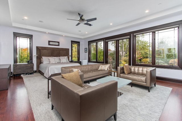 bedroom with dark hardwood / wood-style flooring, ceiling fan, and a tray ceiling