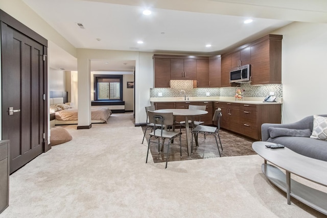 kitchen with light carpet, sink, dark brown cabinetry, and tasteful backsplash