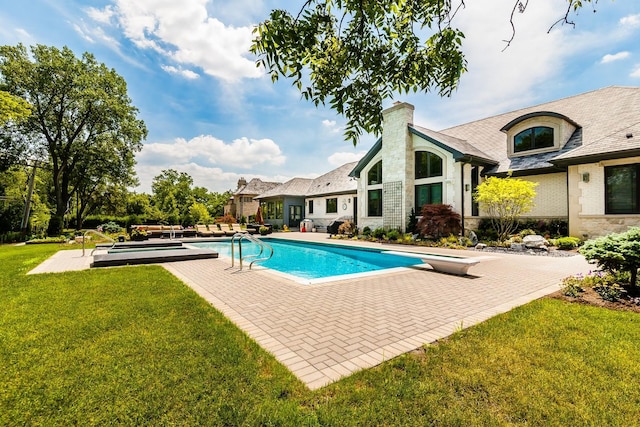 view of swimming pool with a lawn, a patio area, and a diving board