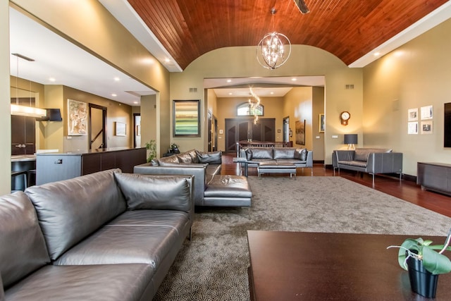 living room featuring dark hardwood / wood-style floors, wood ceiling, a chandelier, and a towering ceiling