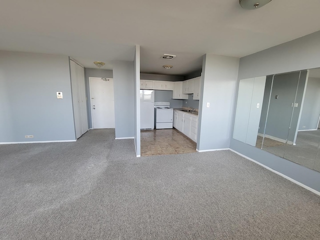 unfurnished living room with sink and light colored carpet